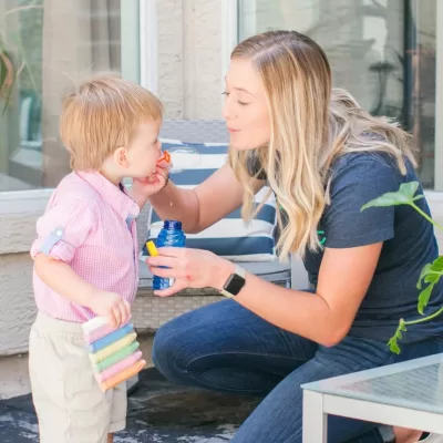 A Time Out Sitter blowing bubbles with a young boy while babysitting.