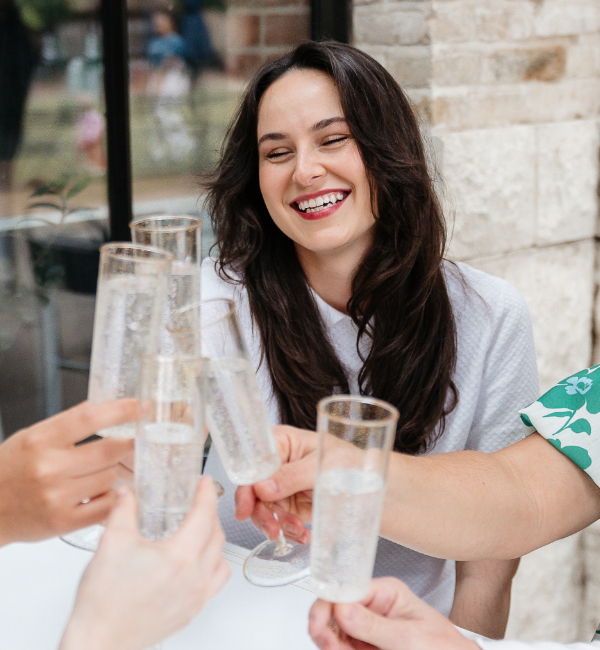 Women sitting outside and clinking their glasses together.