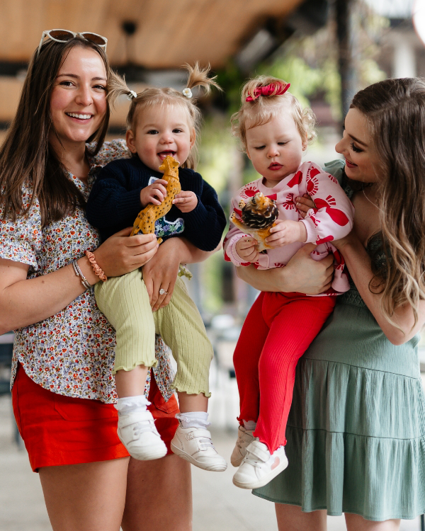 Two women holding two children outside.